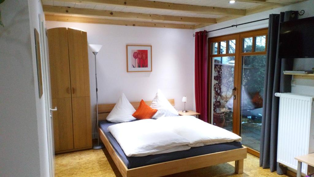 a bedroom with a bed with white sheets and orange pillows at Apartment mit Gartenblick in Eckersdorf