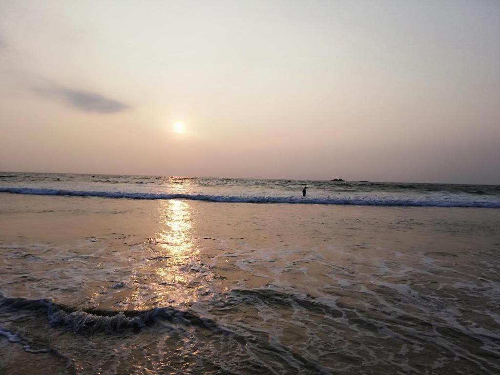 - un coucher de soleil sur la plage avec une personne dans l'eau dans l'établissement Nisadi Villa, à Bentota