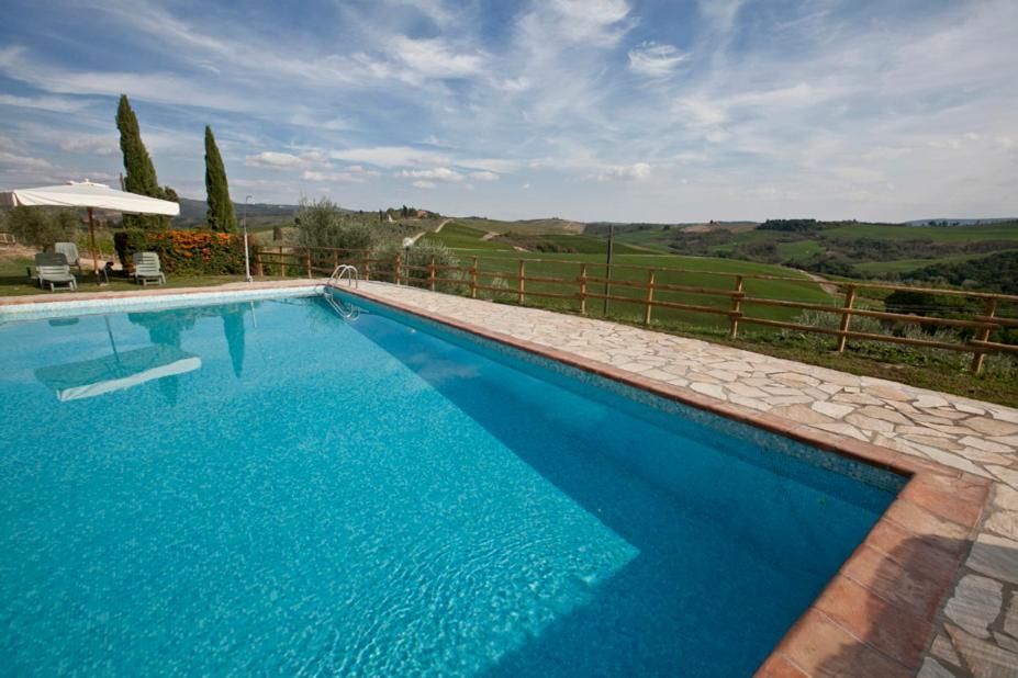 a large blue swimming pool with a fence at Agriturismo il Torrione in Poggibonsi