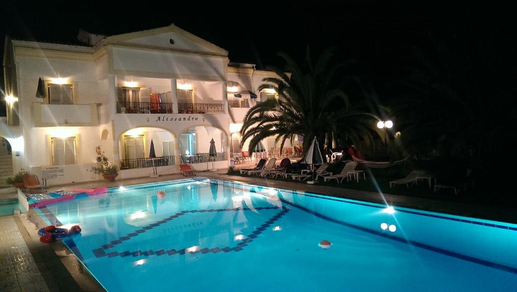 a swimming pool in front of a building at night at Alessandro in Sidari