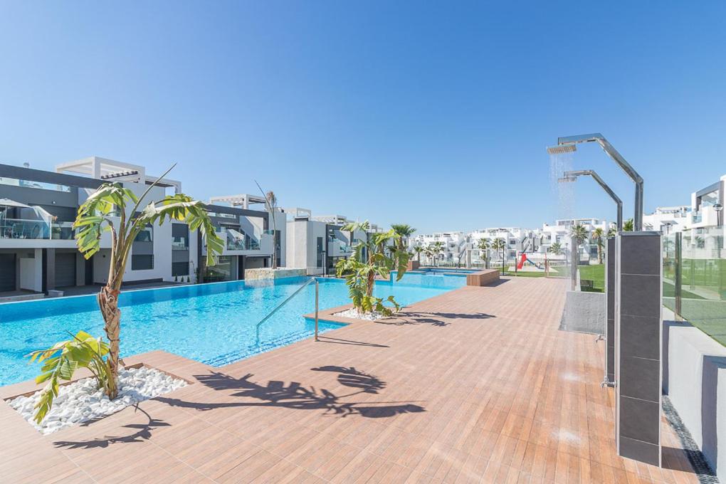 a swimming pool with palm trees on a building at Calle Bullas Topfloor lejlighed in Torrevieja