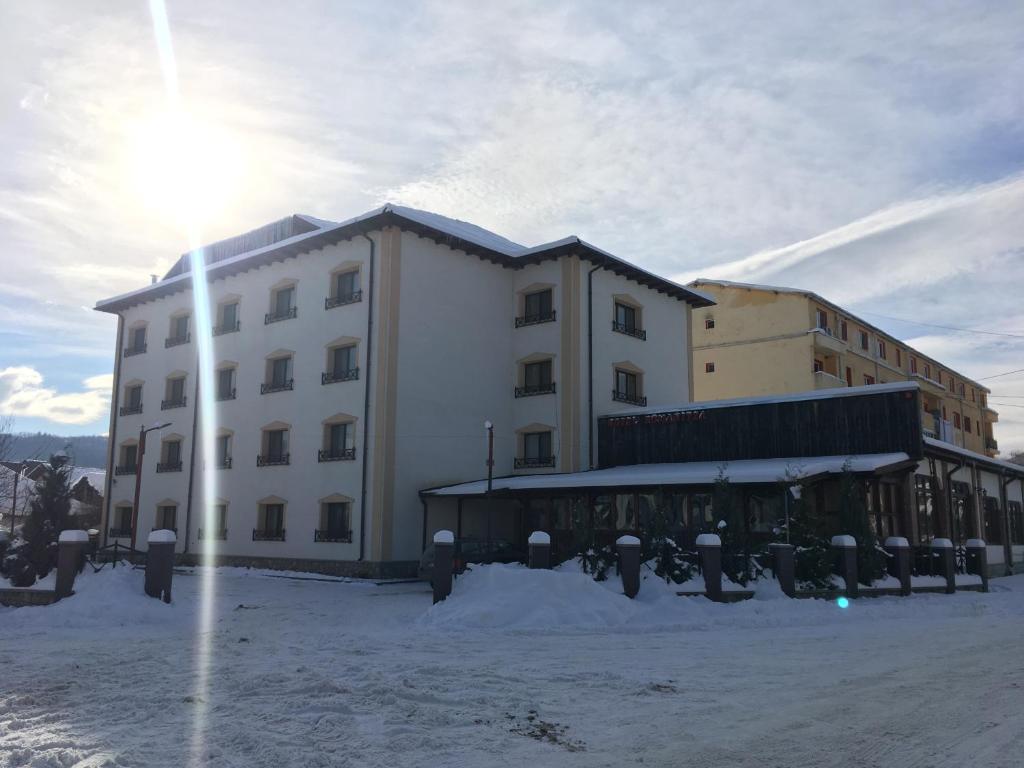 a large white building with snow in front of it at Vila Romanitza in Dărmăneşti