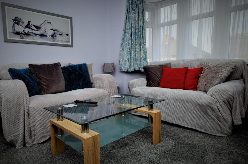 a living room with two couches and a glass coffee table at The Blackpool Apartment in Blackpool