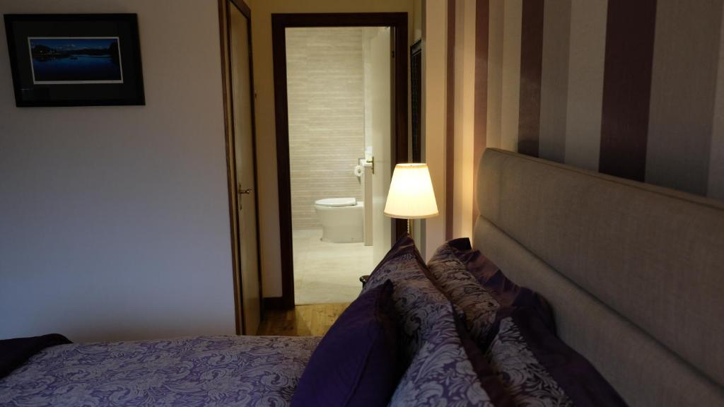 ein Schlafzimmer mit einem Bett und einer Lampe sowie ein Badezimmer in der Unterkunft Ardenlea in Kyle of Lochalsh