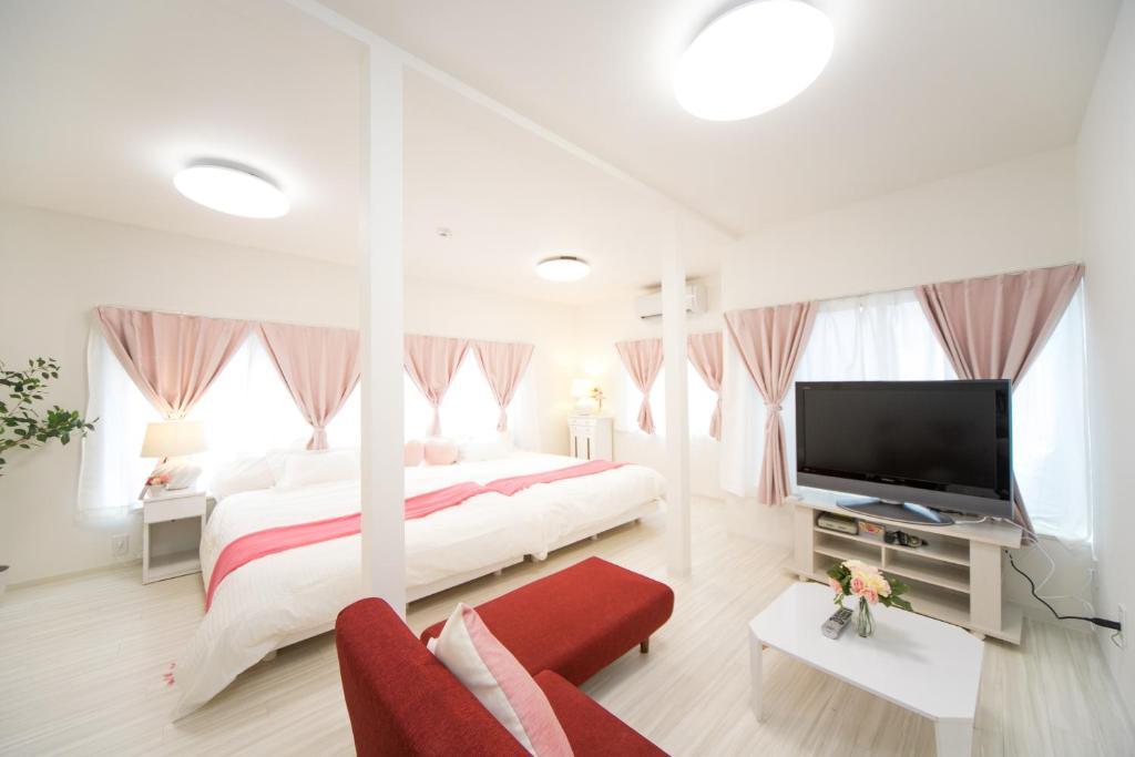 a white bedroom with a large bed and a flat screen tv at Awaji Horiday Inn Kariya in Awaji