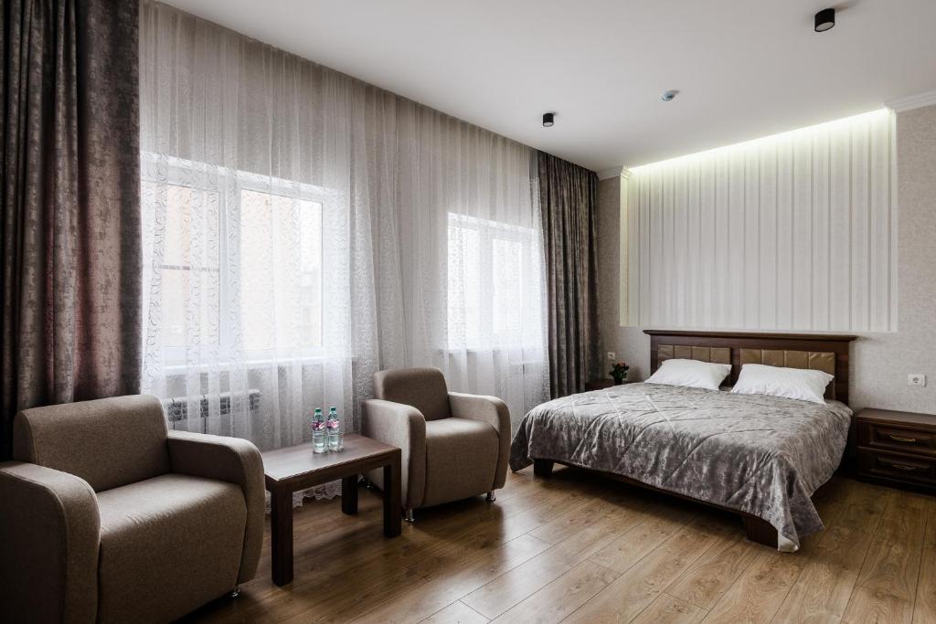 a bedroom with a bed and a chair and window at Nova Hotel in Astrakhan