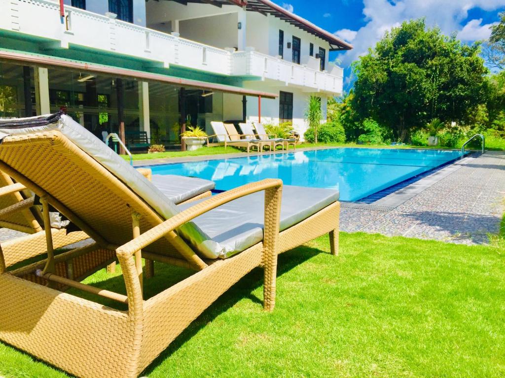 a swimming pool with two lounge chairs next to a house at Saman Resort Yala in Tissamaharama