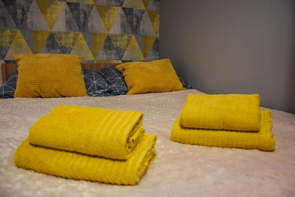 Una cama con toallas amarillas encima. en Mogilska Tower + garaż en Cracovia