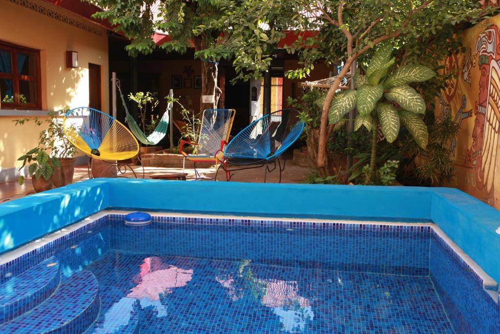 a blue swimming pool with chairs and umbrellas at Hostal La Tortuga Booluda in León