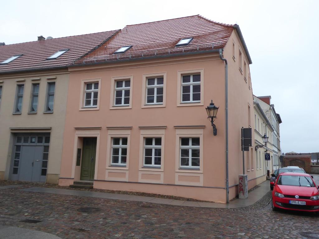 um edifício com um carro vermelho estacionado em frente dele em Altstadt-Ferienwohnungen Neuruppin em Neuruppin