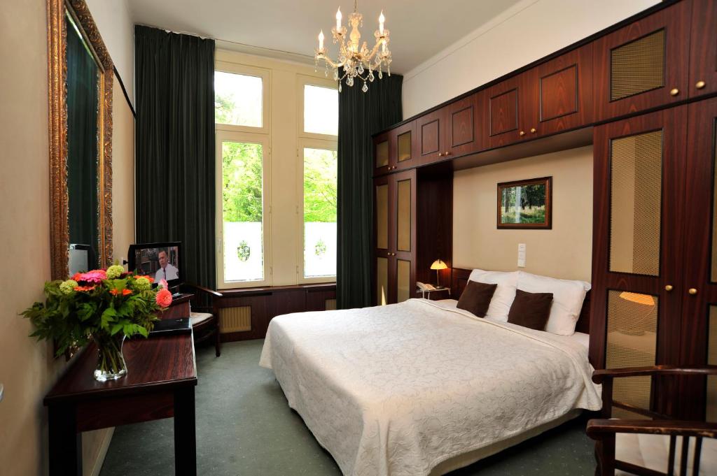 a bedroom with a large bed with a large wooden headboard at Parkhotel Mastbosch Breda in Breda