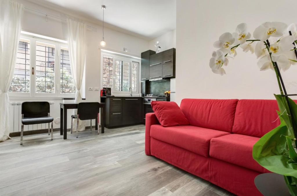 uma sala de estar com um sofá vermelho e uma cozinha em Porta Latina Suite - Private Apartment Rome's Center em Roma