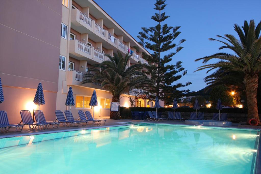 uma piscina em frente a um hotel à noite em Zakantha Beach em Argasi
