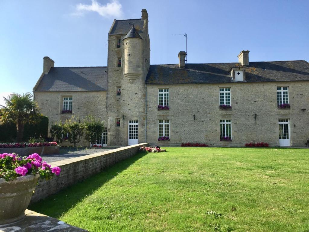 un viejo castillo con un patio de hierba delante de él en Grand gîte de la Ferme De La Tourelle, en Longues-sur-Mer