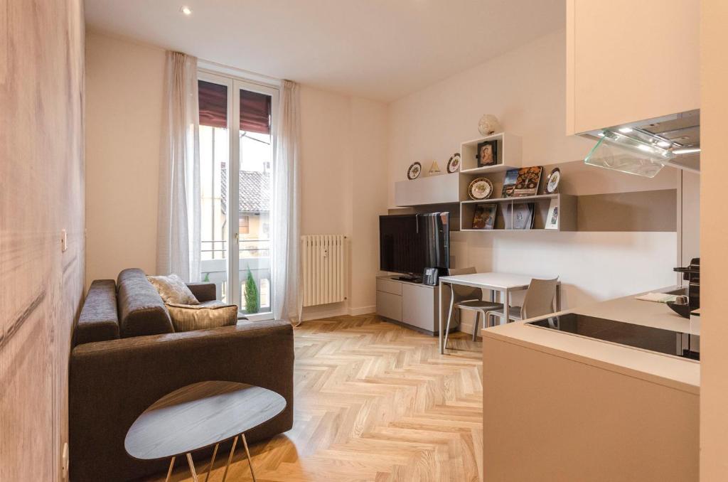 Una sala de estar con un sofá y una cocina. en Calzolerie Luxury Apartment, en Bolonia