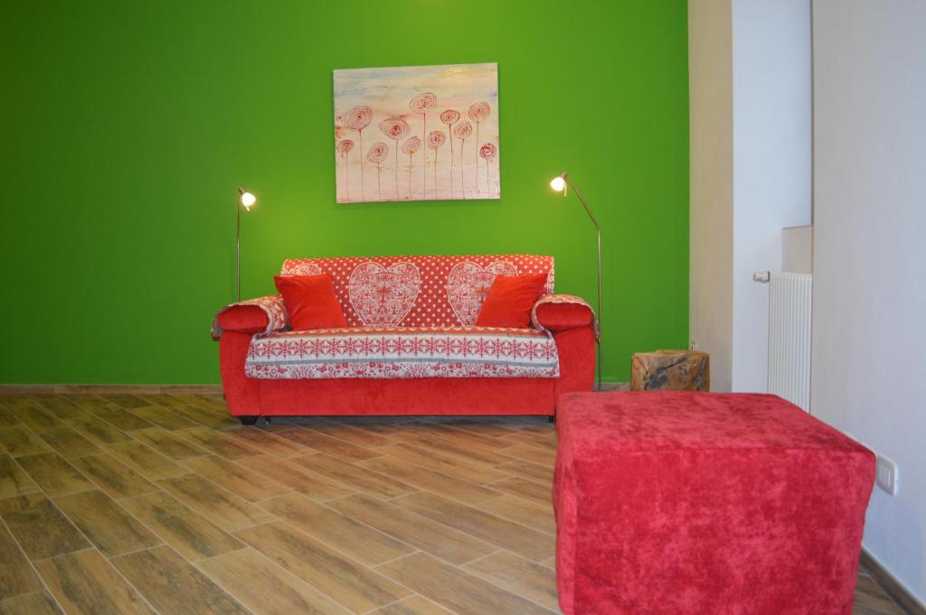 un soggiorno con divano rosso e parete verde di Parravicini Red Flower apartment a Tirano