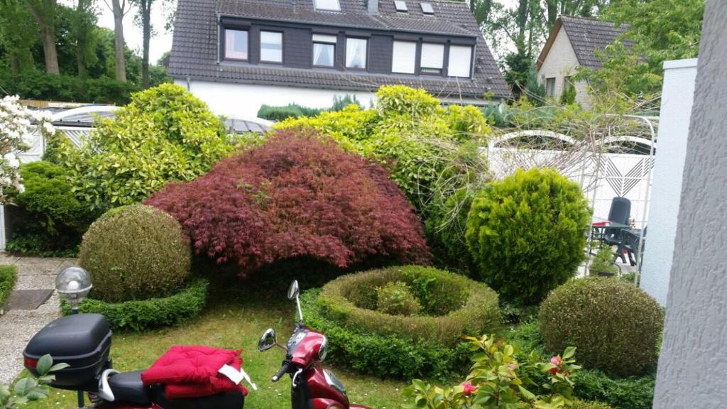 einen Garten mit Büschen und einem Roller vor einem Haus in der Unterkunft Düsseldorf Messe -Apartment Milan in Düsseldorf