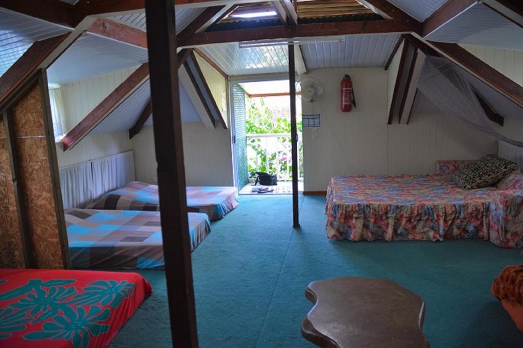 a room with two beds and a chair in it at Fare Maheata in Pihaena