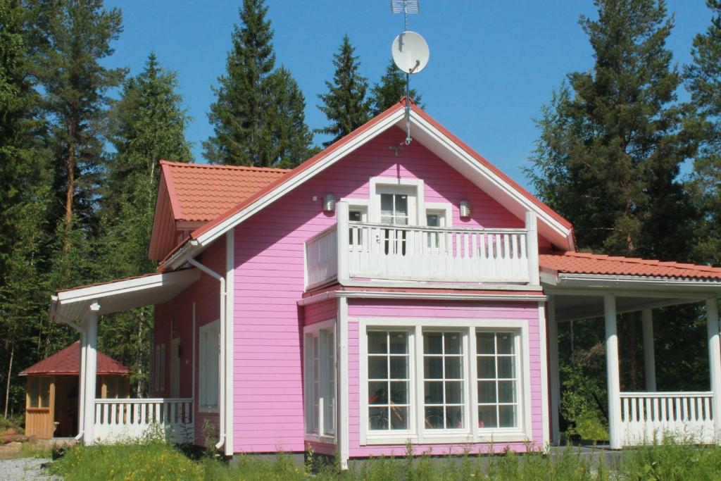 uma casa rosa com um branco em Коттедж в Финляндии, Enonkoski (розовый) em Enonkoski