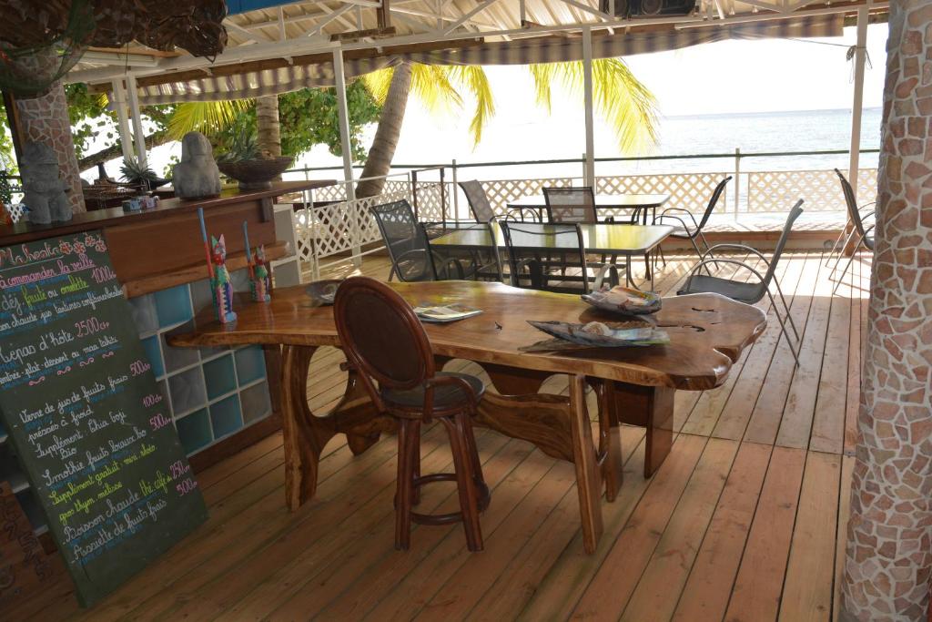 a wooden table and chairs on a deck with the beach at Fare Maheata in Pihaena