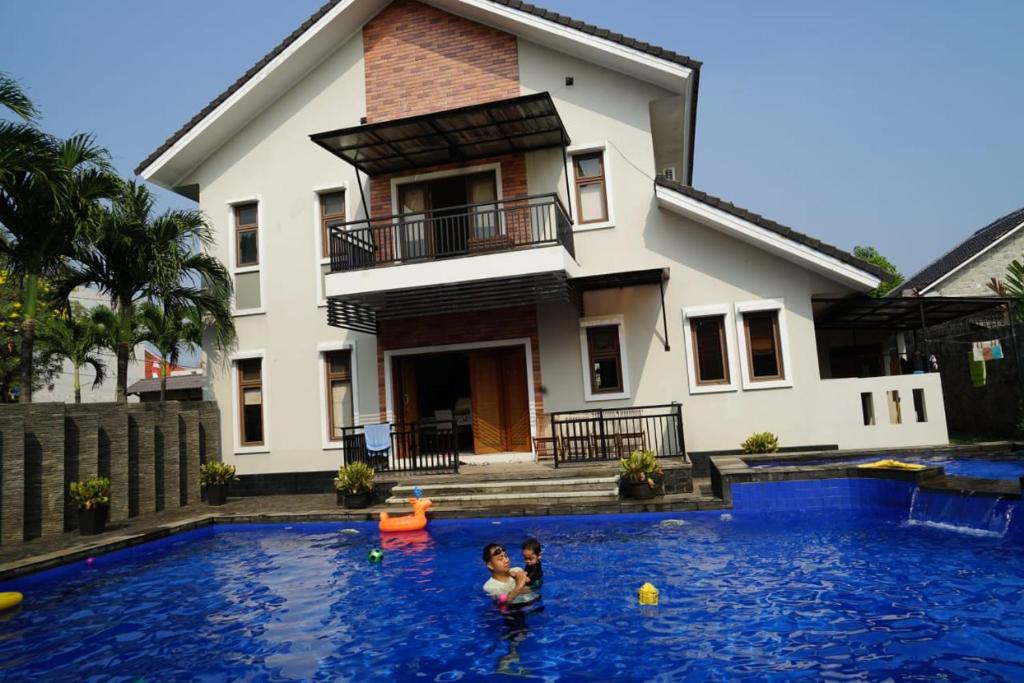 due persone in una piscina di fronte a una casa di Pesona Air - Villa and Private Pool a Depok