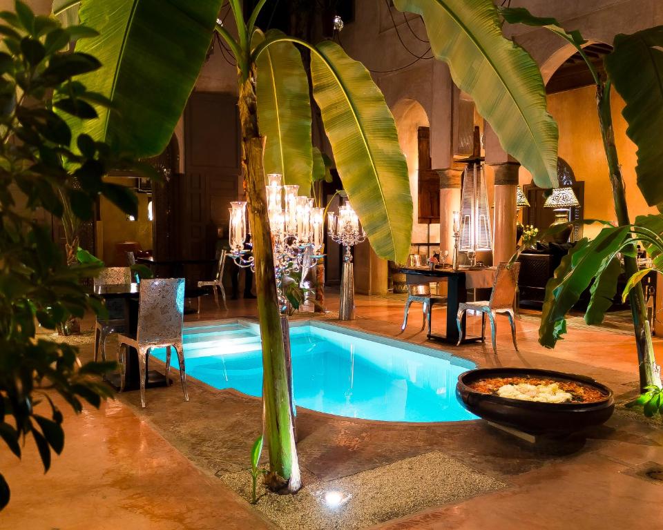 einen Pool mit einer Palme neben einem Esszimmer in der Unterkunft Riad Noir d'Ivoire in Marrakesch