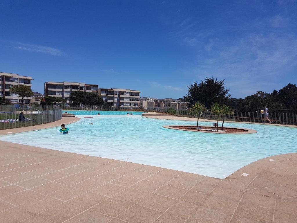 a large blue swimming pool with people in it at Departamento en Lomas de Papudo II in Papudo