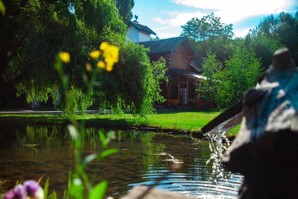 a stone statue next to a pond in front of a house at Hostel Meridiano 71 in El Bolsón