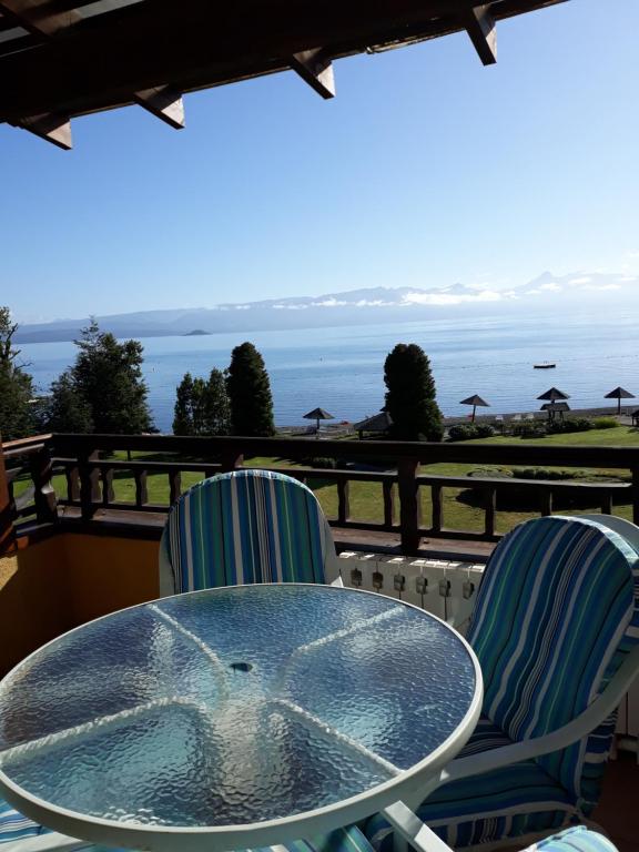 una mesa y sillas en un balcón con vistas al océano en Condominio La Puntilla Km 2 Camino Villarrica Pucon, en Villarrica