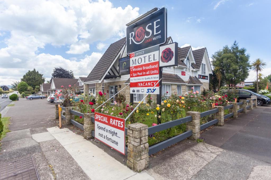 a sign for a motel with flowers in front of a house at Rose Court Motel in Rotorua