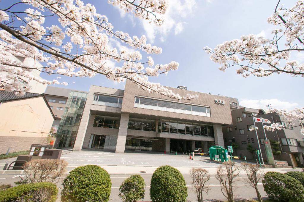 een universiteitsgebouw met witte raakura bomen ervoor bij KKR Hotel Kanazawa in Kanazawa