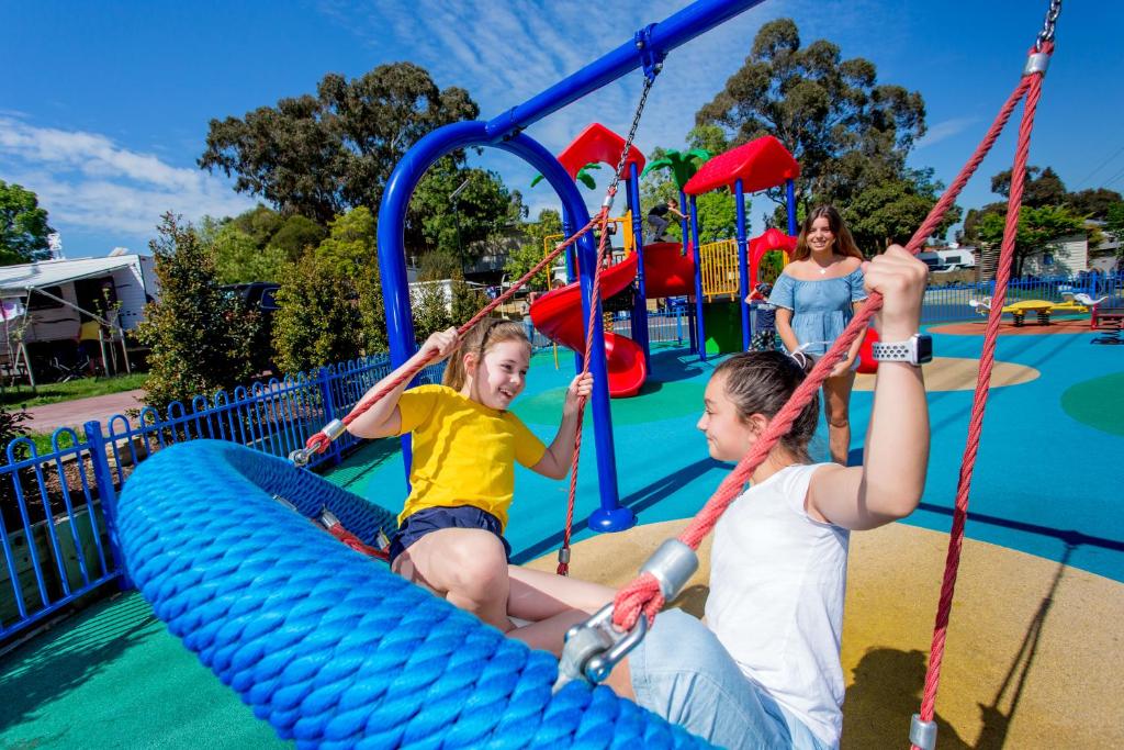 zwei Kinder reiten auf einem aufblasbaren Floß auf einem Spielplatz in der Unterkunft BIG4 Melbourne Holiday Park in Melbourne