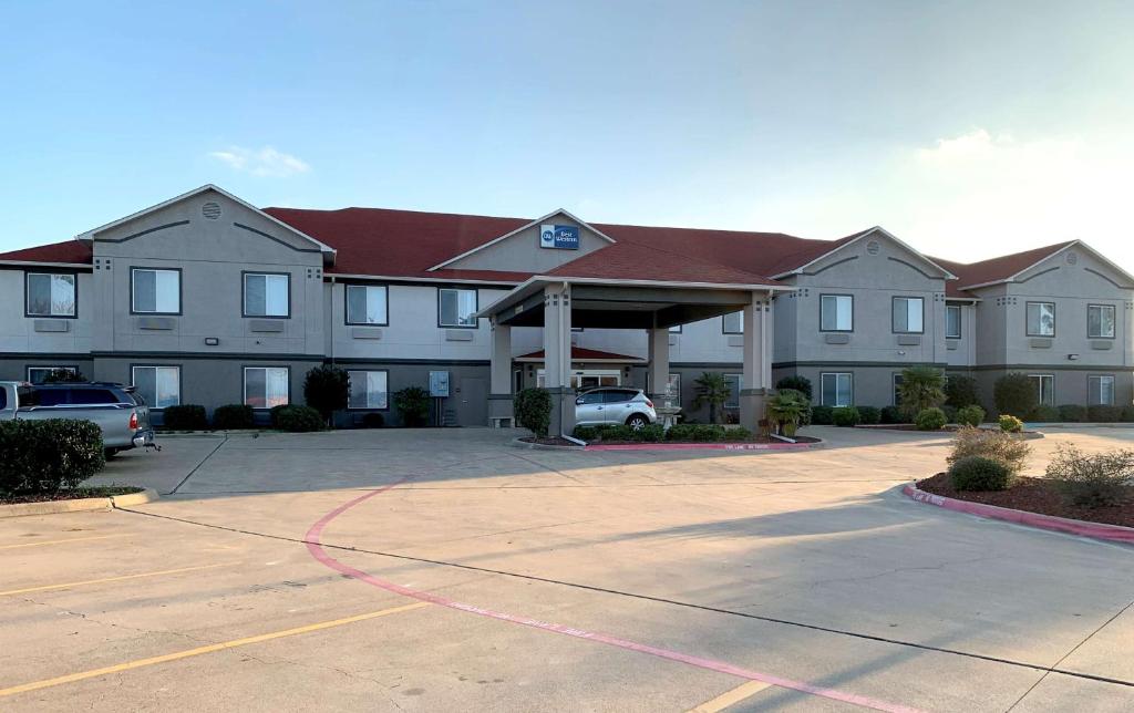 un gran edificio con un estacionamiento delante de él en Best Western Limestone Inn and Suites, en Mexia