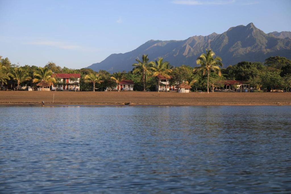 a body of water with houses and palm trees and mountains at Matema Lake Shore Resort in Matema Beach