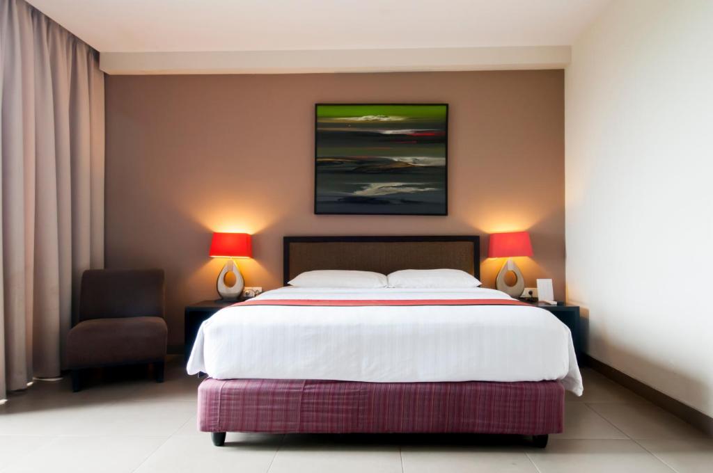 1 dormitorio con 1 cama grande y 1 silla en 100 Sunset Kuta Hotel & Ballroom, en Kuta