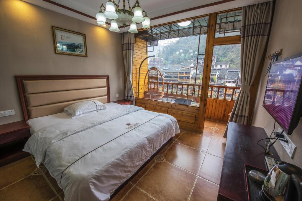 鳳凰的住宿－鳳凰記憶臨江客棧，一间卧室设有一张大床和一个大窗户