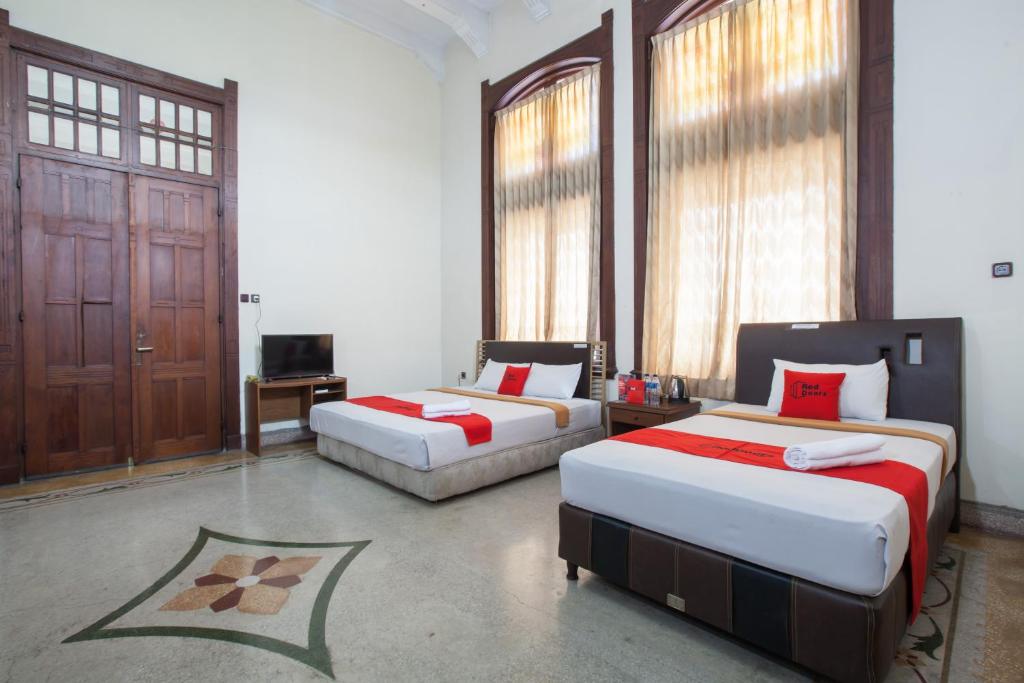 a bedroom with two beds and a television in it at RedDoorz @ Lawang in Malang