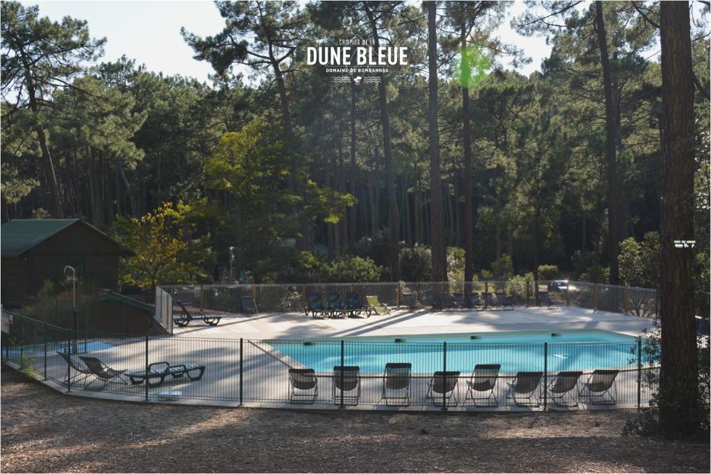 a swimming pool with chairs and a fence around it at Wellness Sport Camping - La Dune Bleue in Carcans