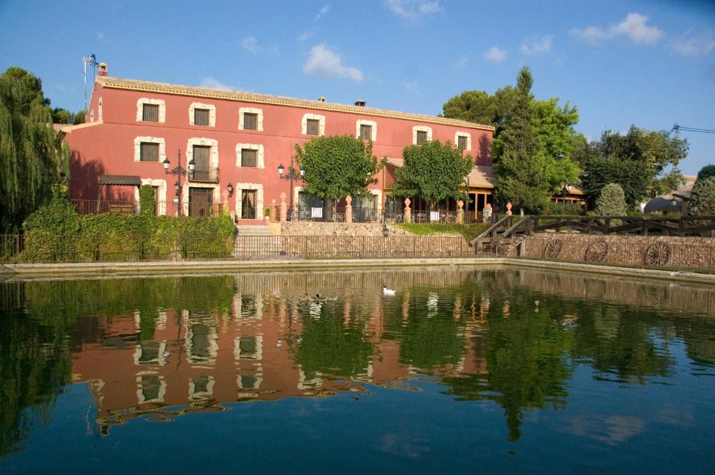 czerwony budynek obok rzeki z budynkiem w obiekcie Hotel Caseta Nova w mieście Castalla