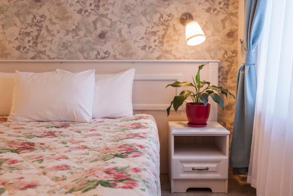 een slaapkamer met een bed en een plant op een nachtkastje bij Art-Hotel Centralnyi in Kostroma