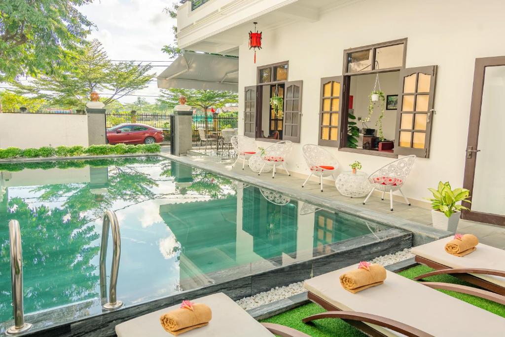 a swimming pool with tables and chairs next to a house at Horizon 2 villa in Hoi An