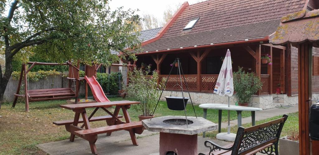 a backyard with benches and a fire pit and a house at Alexandra Vendégház in Abádszalók