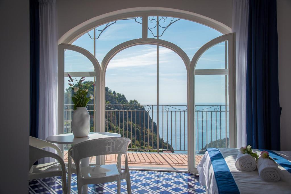 ein Schlafzimmer mit einem großen Fenster sowie einem Tisch und Stühlen in der Unterkunft Palazzo San Giovanni Amalfi Coast in Scala
