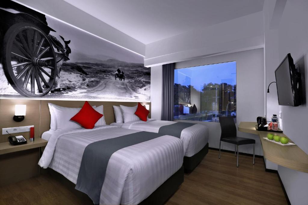 a hotel room with a large bed with a wheel on the wall at NEO+Waru-Sidoarjo by ASTON in Sidoarjo
