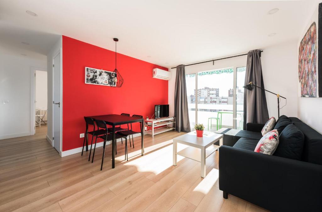 a living room with a black couch and a red wall at Ever House IFEMA Mar de Cristal in Madrid