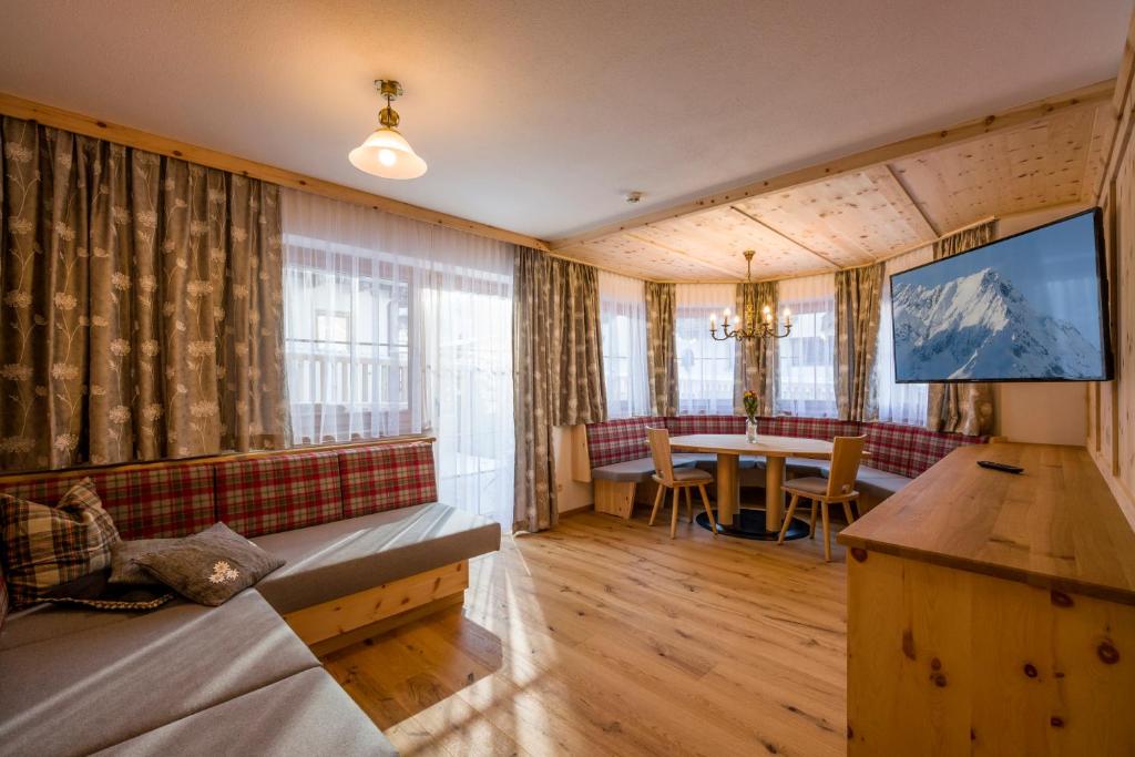 ein Wohnzimmer mit einem Tisch und einem großen Bildschirm in der Unterkunft Appartementhaus Adlerblick in Mayrhofen