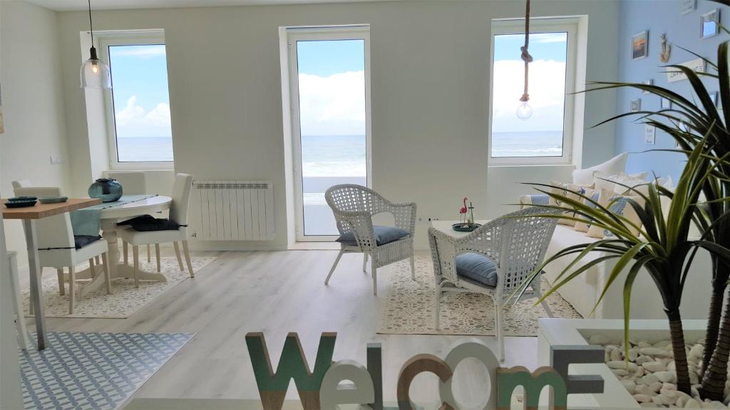 een woonkamer met een tafel en stoelen en de oceaan bij The Shore @ BaíaBeach - Waterfront in Espinho