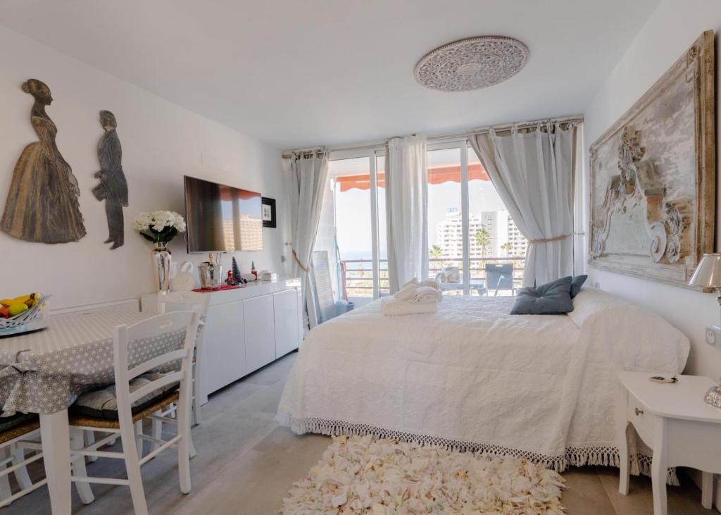Sweet home deluxe في بلايا ذي لاس أميريكاس: غرفة نوم بيضاء مع سرير وطاولة ومكتب