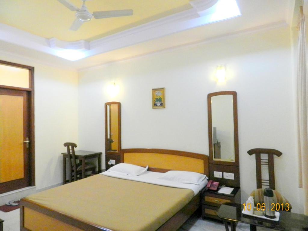 a bedroom with a bed and two mirrors on the wall at Hotel Tara Palace, Chandni Chowk in New Delhi