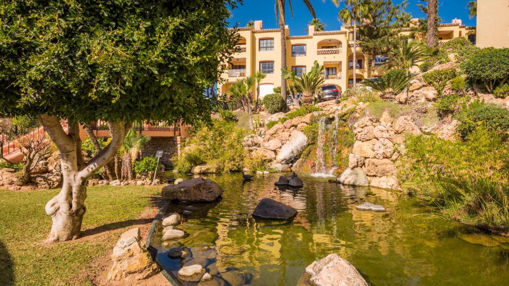 a pond in a garden with a building in the background at Macdonald Doña Lola Resort in La Cala de Mijas